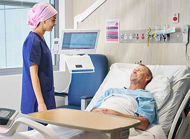 A nurse talking to a patient in a bed 